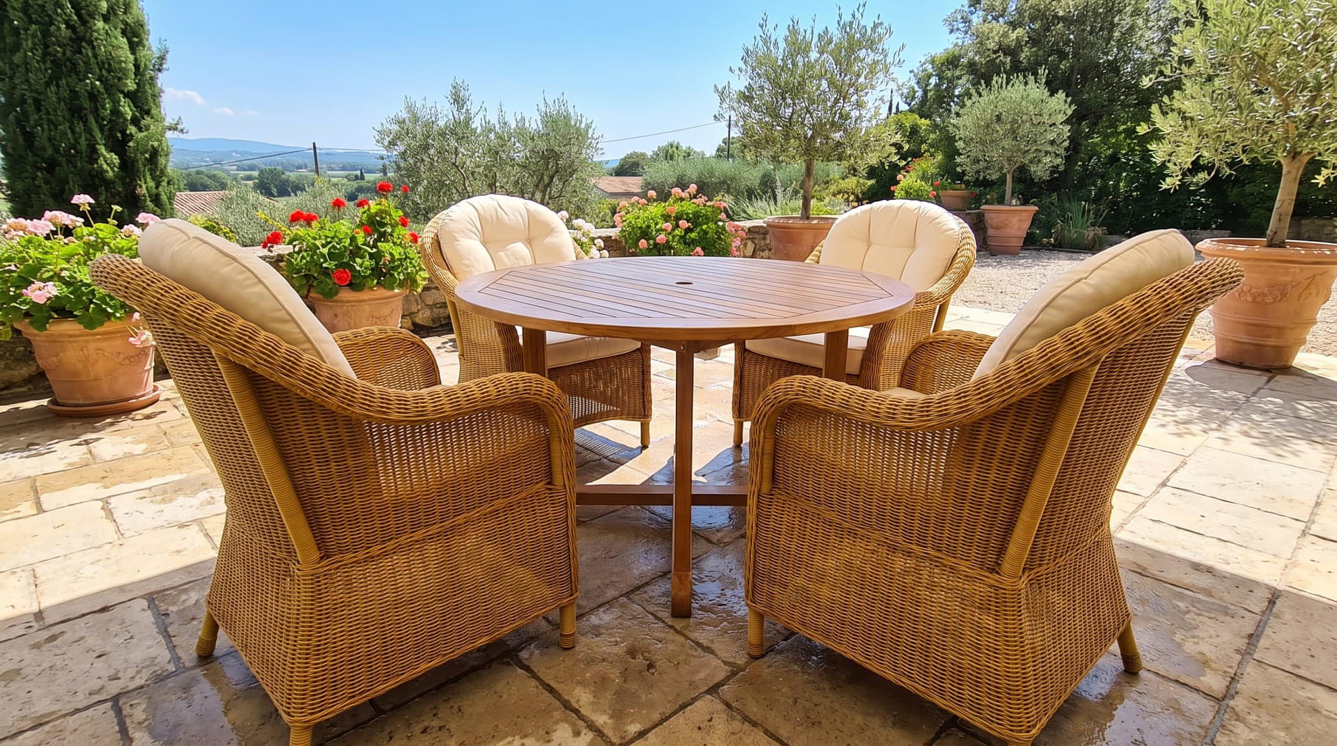 Clean, freshly scrubbed outdoor patio furniture in bright sunlight - wicker chairs and a teak table on a terrace